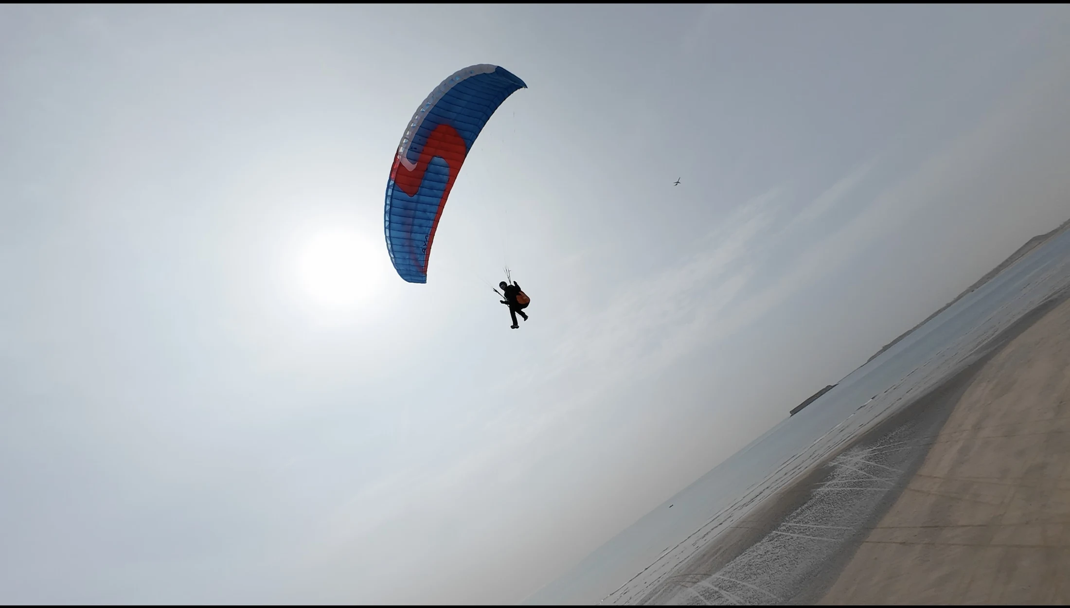 Die Gleitschirmfliegerin hebt über dem Strand ab.