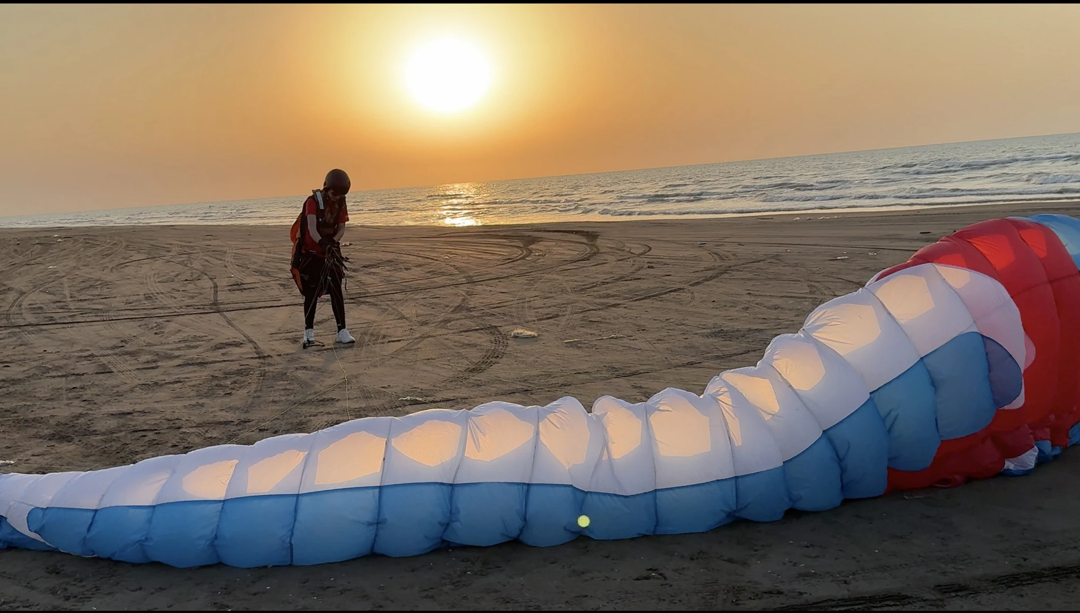 Eine Gleitschirmfliegerin bereitet sich am Strand auf den Flug vor.